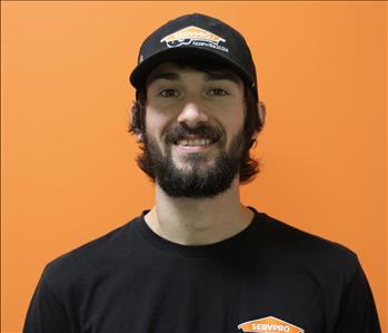 A man in a black shirt standing in front of an orange background