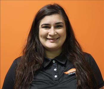 A woman in a black shirt standing in front of an orange background