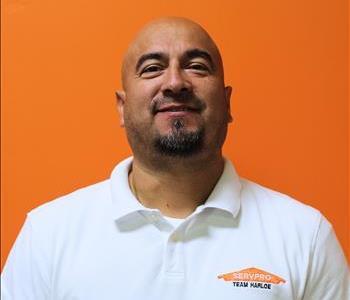 A man in a white shirt standing in front of an orange background