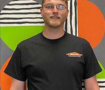 Levi (man) standing in front of green and orange mural background 